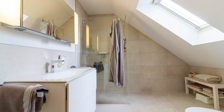 Das Schlafzimmerbad: Klar strukturiert, stilvoll modernisiert und mit großzügiger Dusche – ideal für den täglichen Komfort.