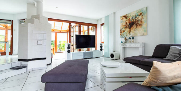 Ein großzügiges Raumgefühl, große Fensterflächen und direkter Zugang zum Wintergarten machen dieses Wohnzimmer zum Herzstück des Hauses.