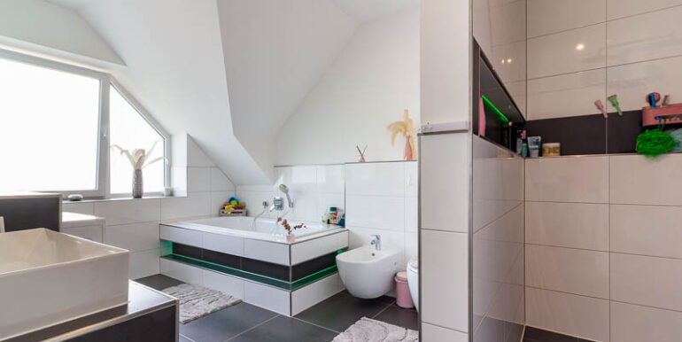 Elegantes Badezimmer mit klaren Linien, großformatigen Fliesen und stimmiger Lichtgestaltung.