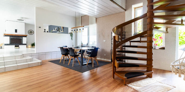 Offene Grundrissgestaltung mit Blick zur Küche und eleganter Holztreppe – ein echtes Wohnhighlight.