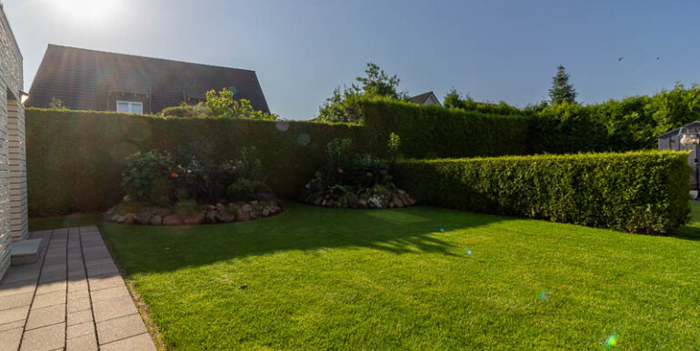 Pflegeleichter Garten mit blickdichtem Heckenzaun und liebevoll angelegten Beeten – perfekte Privatsphäre für erholsame Stunden im Grünen.