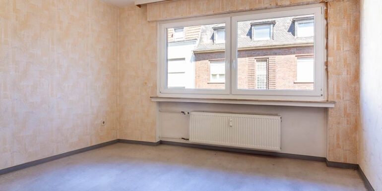 Helles Schlafzimmer mit großem Fenster – viel Potenzial für einen gemütlichen Rückzugsort.